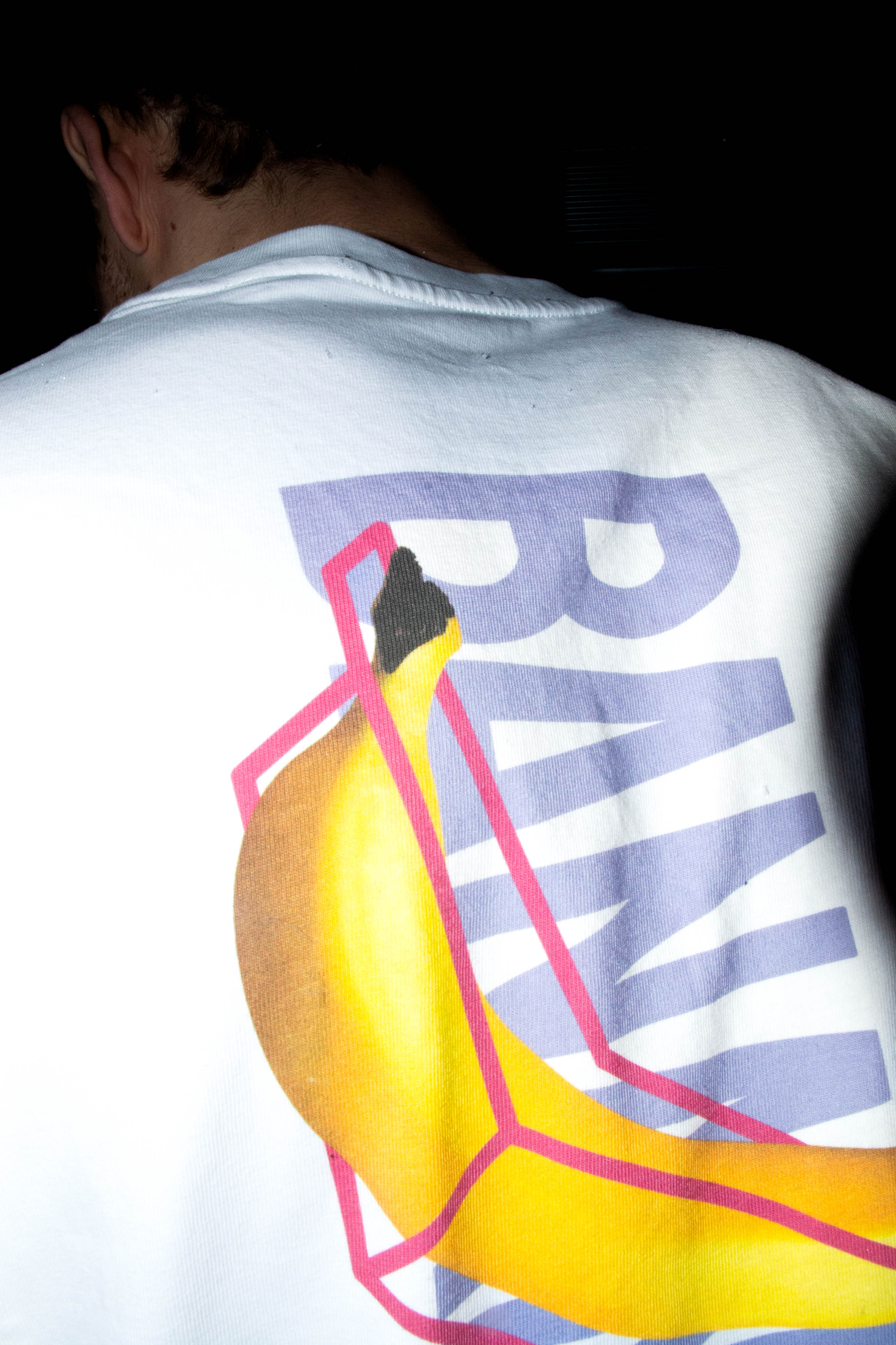 Leon Scholl trägt dsa Banana Climbing Shirt in der Farbe weiß. Backprint eine Banane und das Banana Logo hitnerdran der Schriftzug BANANA - Nahaufnahme, CloseUp
