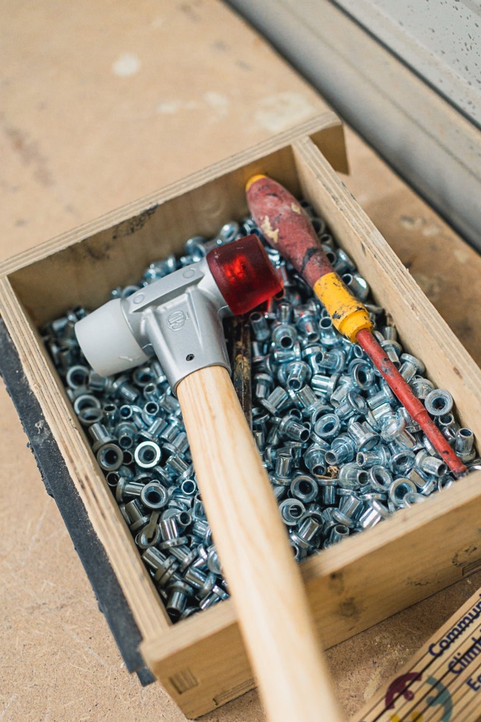 M5 Einschlaghülsen, ein Hammer und ein Schraubendreher in einer Holzkiste.