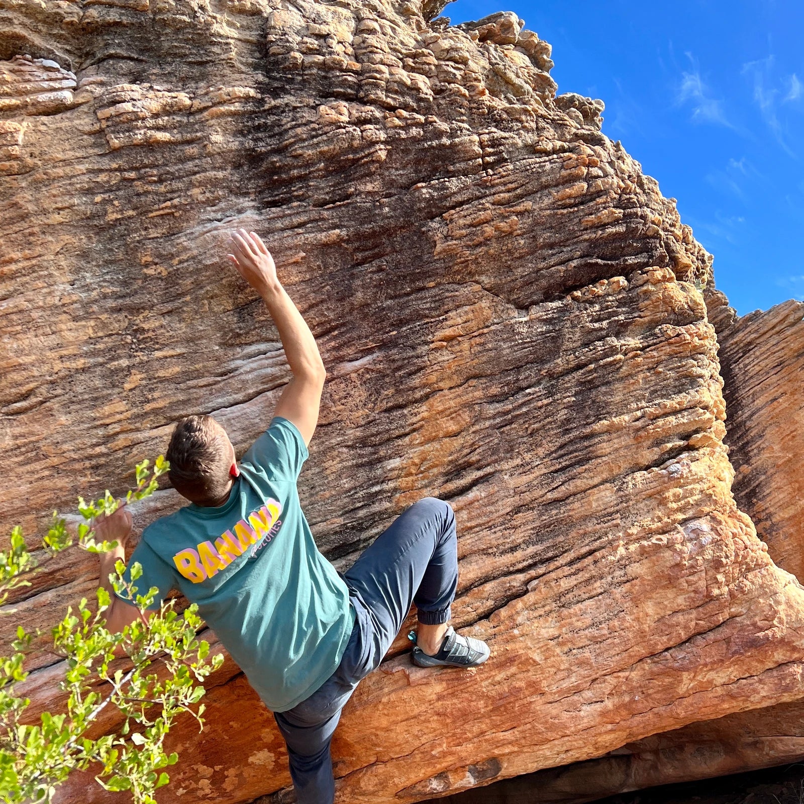 Ein Mann in einem Banana Volumes limited edition T-Shirt klettert an einem Felsen.