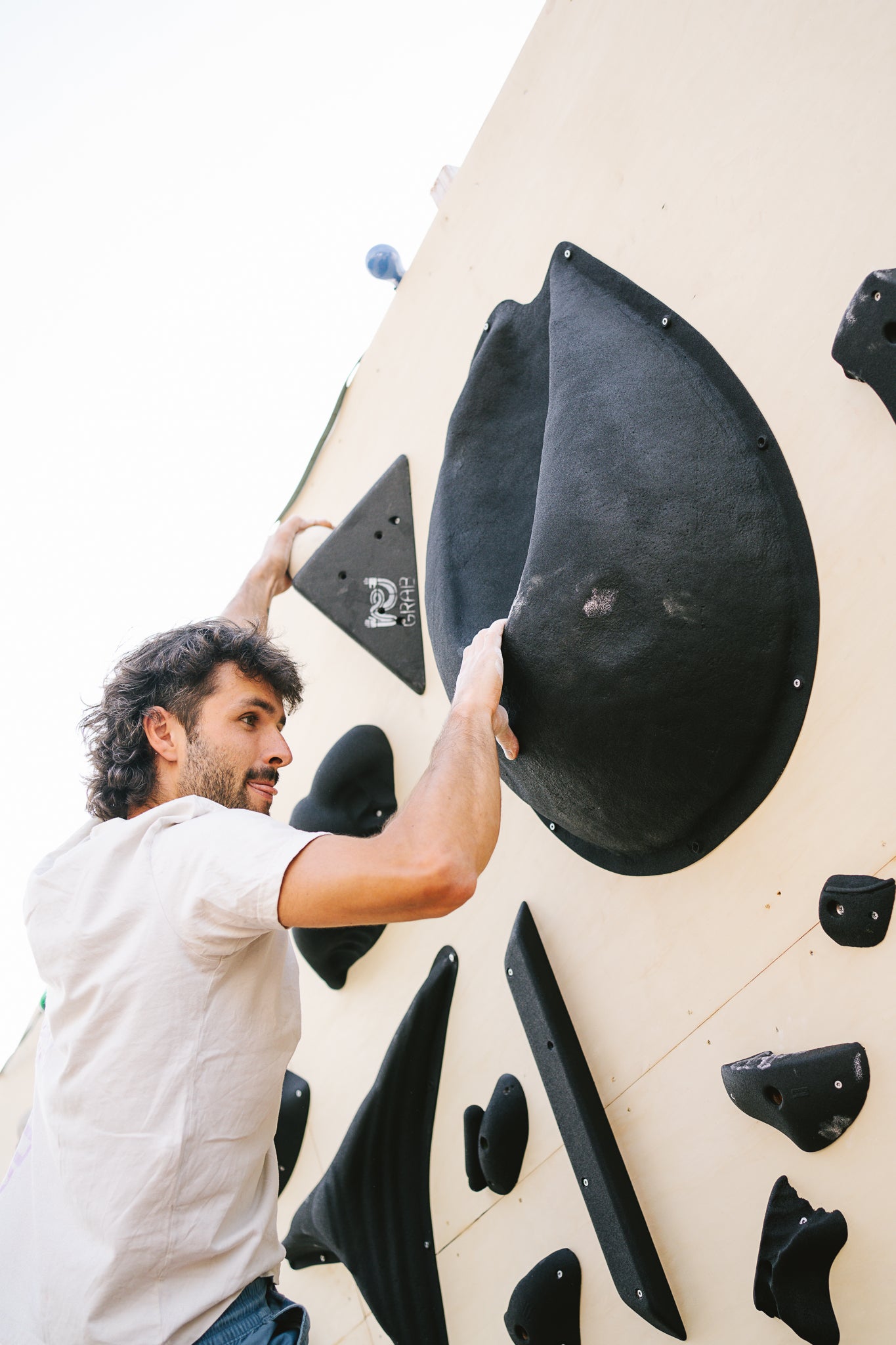 Johannes Hoffmann von Banana Volumes klettert an einer Boulderwand mit von ReGrab generalüberholten Griffen.