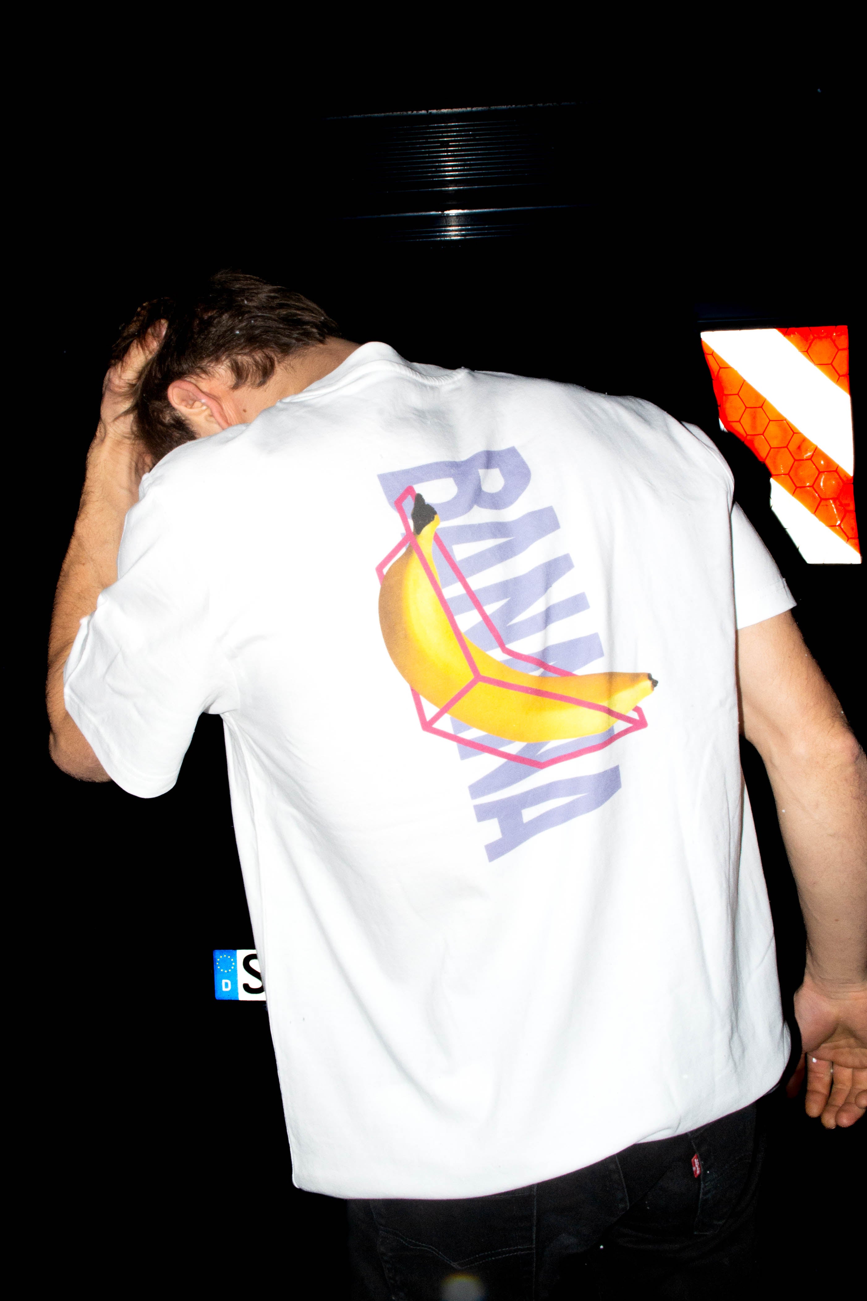 Leon Scholl trägt dsa Banana Climbing Shirt in der Farbe weiß. Backprint eine Banane und das Banana Logo hitnerdran der Schriftzug BANANA