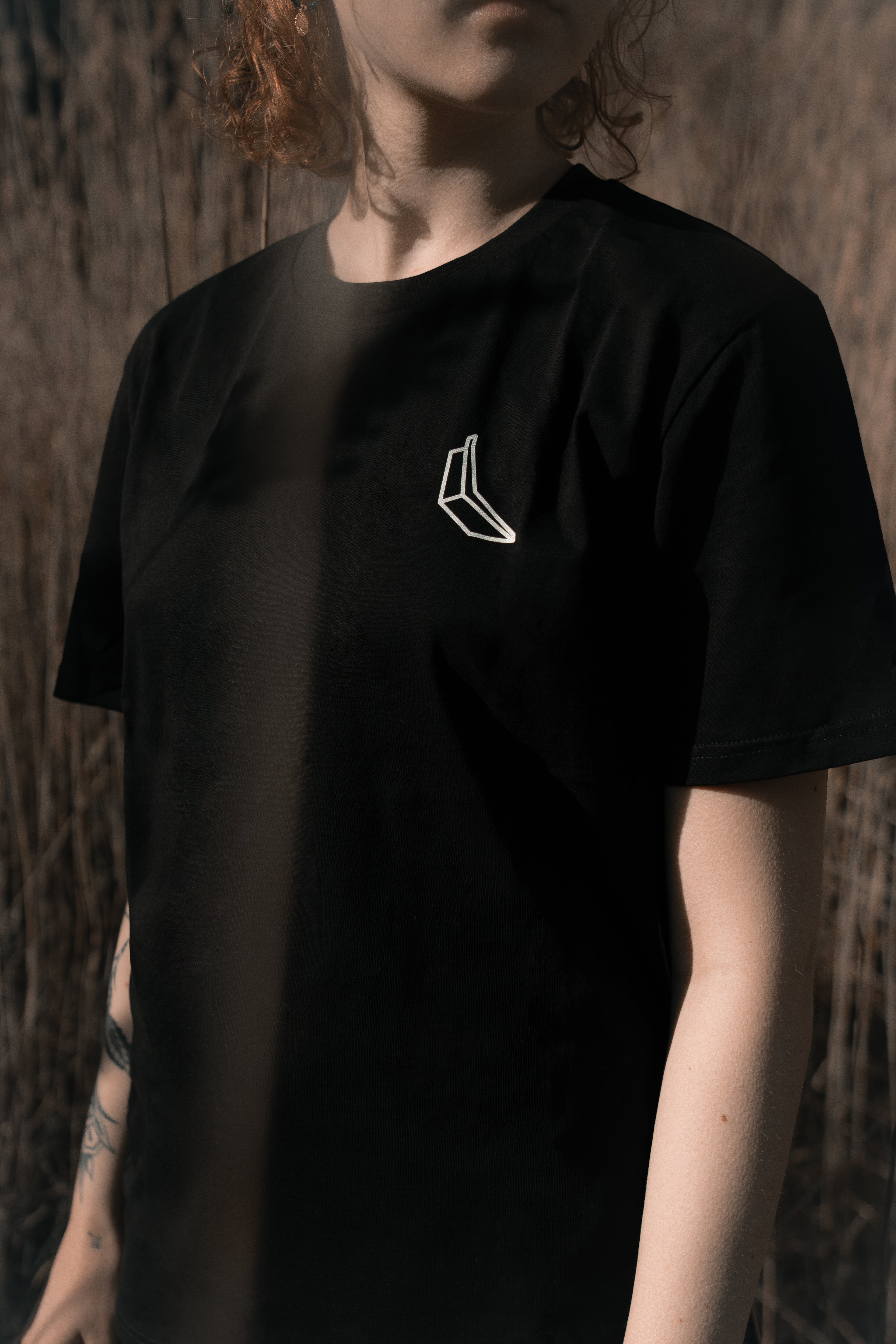 Man sieht den Oberkörper einer Frau, sie trägt ein schwarzes Banana Volumes T-Shirt.