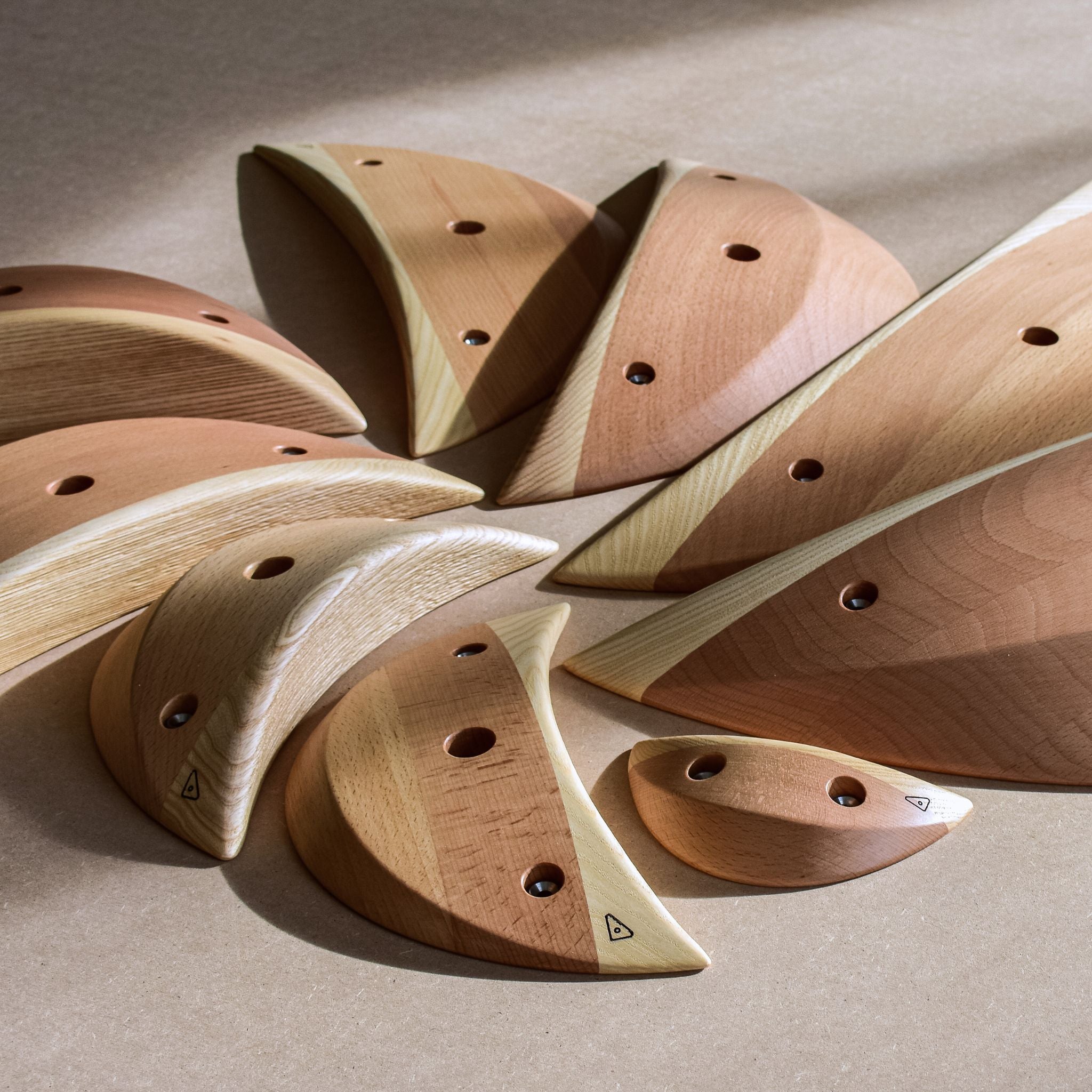 Neun in einem Kreis angeordnete Klettergriffe der Marke Handfest aus Holz.