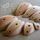 Acht Klettergriffe der Marke Handfest aus Holz und das Logo der Marke.
