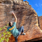 Ein Mann in einem Banana Volumes limited edition T-Shirt klettert an einem Felsen.